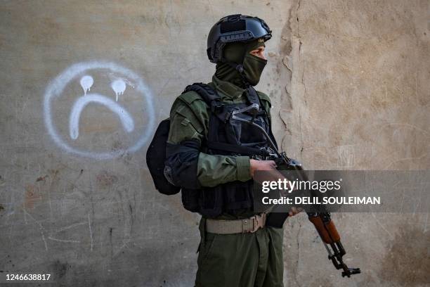 Member of the Syrian Kurdish Asayish security forces walks past a house during a raid against suspected Islamic State group fighters in Raqa, the...