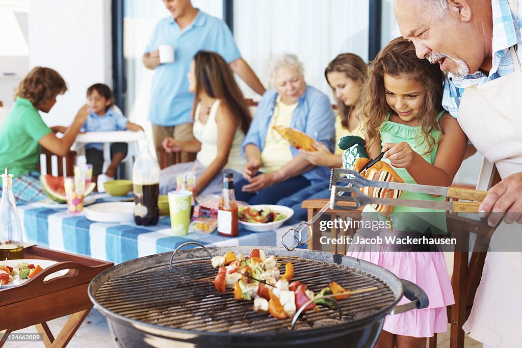 Young girl and older man grilling at barbecue