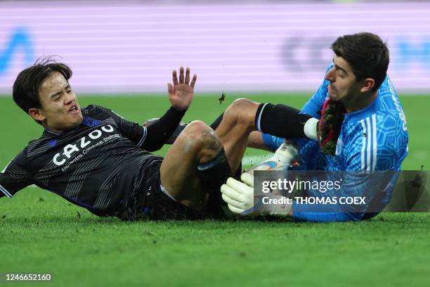 Real Sociedad's Japanese forward Takefusa Kubo vies with Real Madrid's Belgian goalkeeper Thibaut Courtois during the Spanish league football match...