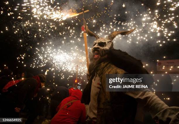 Participant with a demon mask brandishes a stick with fireworks among revellers during the traditional Correfoc festival in Palma de Mallorca on...