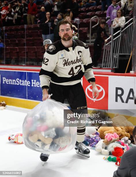 Dylan Mcilrath of the Hershey Bears helps pick up some teddy bears after an American Hockey League game during the "GIANT Teddy Bear Toss" during a...