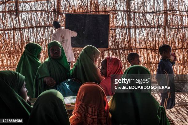 Children sit as a teacher writes on a blackboard in a classroom at a school in the camp for internally displaced people of Farburo in the village of...