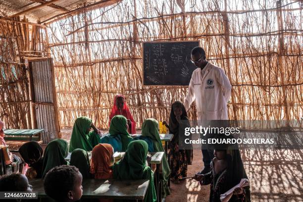 Children talk with a teacher in a classroom at a school in the camp for internally displaced people of Farburo in the village of Adlale, near the...