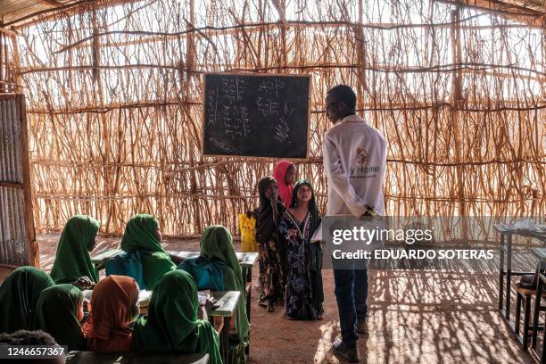 Children talk with a teacher in a classroom at a school in the camp for internally displaced people of Farburo in the village of Adlale, near the...