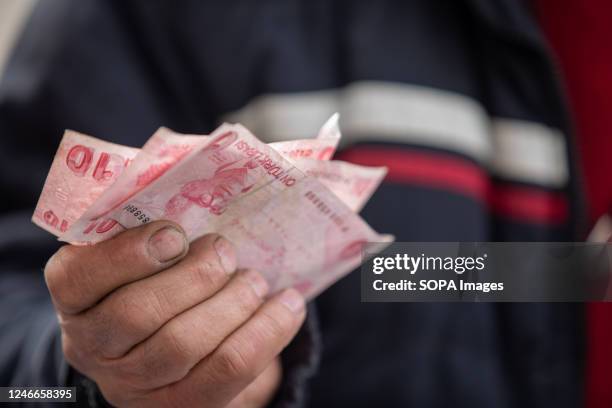 Seller is holding 10 Turkish lira banknotes at a flea market. The flea market, which is set up during the weekends in Ankara Ulus Square, has been...