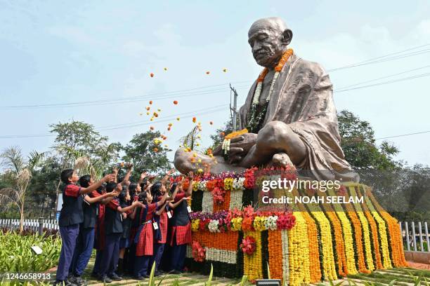 School students scatter flowers on the statue of Mahatma Gandhi on his death anniversary in Hyderabad on January 30, 2023. - The death anniversary of...