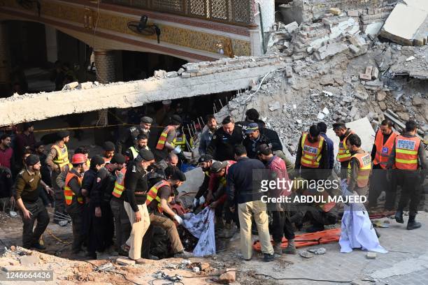 Rescue workers carry the remains of the blast victims from the debris of a damaged mosque after a blast inside the police headquarters in Peshawar on...