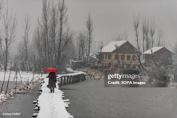 Man with an umbrella walks along a snow covered bridge during snowfall in Srinagar. The Kashmir valley received a fresh snowfall which disrupted the...
