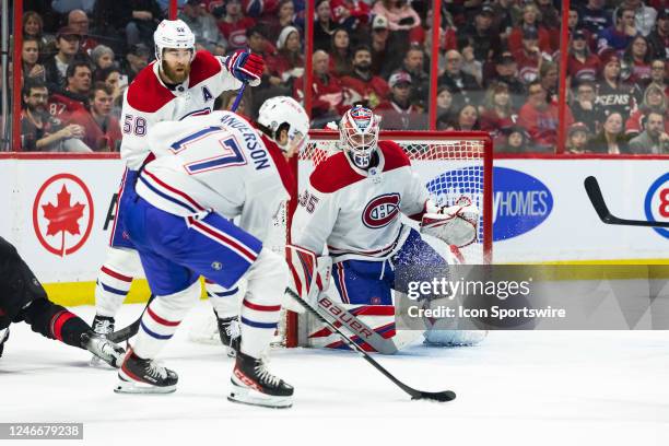 Montreal Canadiens Goalie Sam Montembeault tracks the puck as Right Wing Josh Anderson clears it away and Defenceman David Savard looks on during...