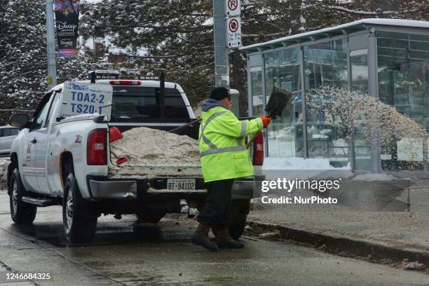 City worker throws road salt near a bus stop to prevent ice build-up after a fresh snowfall in Toronto, Ontario, Canada, on January 29, 2023.