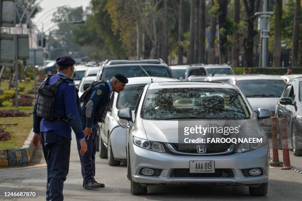 Policeman speaks to a commuter at a checkpoint outside the constitution avenue in Islamabad on January 31, 2023. - Bodies were still being pulled on...