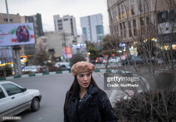 Young Iranian woman wearing a hat looks on while standing on a street-side in northern Tehran at sunset, January 30, 2023. Since the Iranian Islamic...