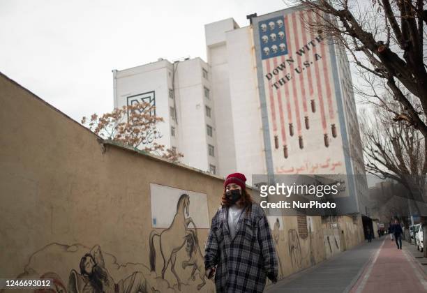 An Iranian young woman walks under an anti-U.S. Mural in downtown Tehran, January 29, 2023. Since the Iranian Islamic Revolution triumphed forty-four...
