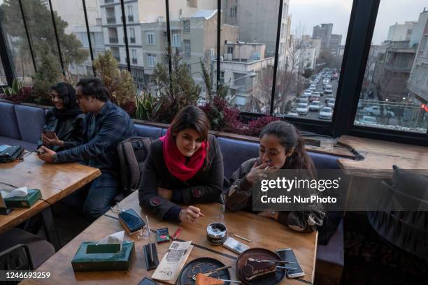 Iranian youths sit together at a cafe in downtown Tehran, January 29, 2023. Since the Iranian Islamic Revolution triumphed forty-four years ago, it...