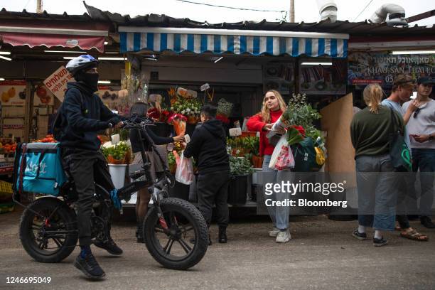 Delivery driver on an e-bike rides past a flower stall at Carmel Market in Tel Aviv, Israel, on Sunday, Jan. 29, 2023. Israeli Prime...