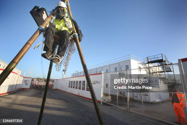 Protester sits on top of a tripod to block access to construction workers watched by a security guard on January 31, 2023 in Full Sutton, United...