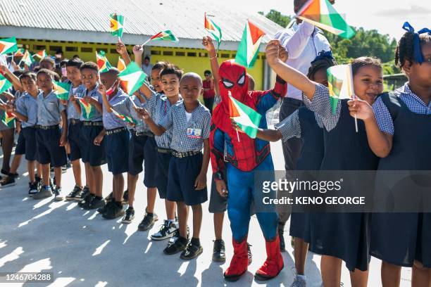 Children wave Guyanese flags while waiting for the arrival of Guyanese actress Letitia Wright at the Patentia Primary School in Georgetown on January...