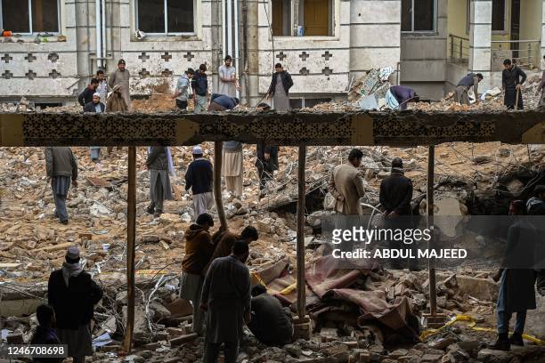 Plain-clothed policemen and labourers remove debris from a damaged mosque following January's 30 suicide blast inside the police headquarters in...