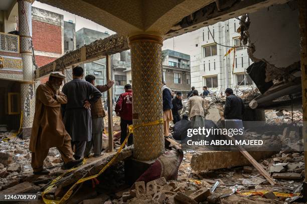 Plain-clothed policemen gather over the rubble of a damaged mosque following January's 30 suicide blast inside the police headquarters in Peshawar on...