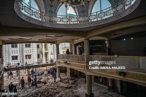 Plain-clothed policemen gather over the rubble of a damaged mosque following January's 30 suicide blast inside the police headquarters in Peshawar on...