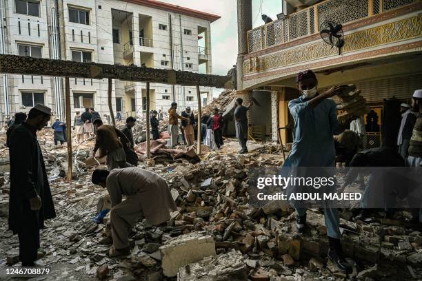 Plain-clothed policemen and labourers remove debris from a damaged mosque following January's 30 suicide blast inside the police headquarters in...