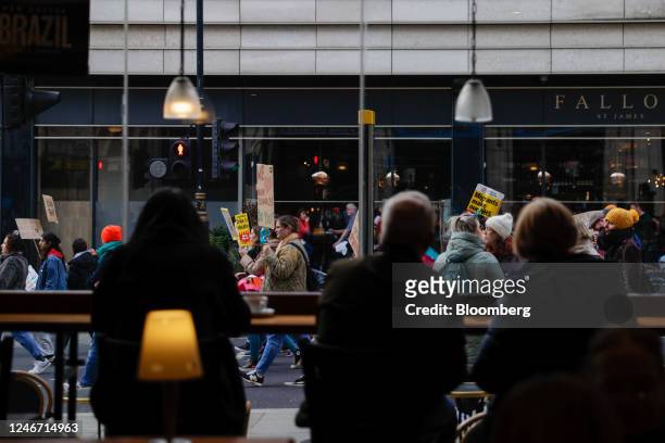 Striking workers march past a coffee shop during joint strike action by train drivers, teachers, university staff and civil servants, in London, UK,...