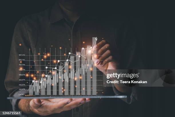 businessmen are using tablet computers to analyze trends of fast-growing businesses with rising graph bars on a black background. - business performance stock-fotos und bilder