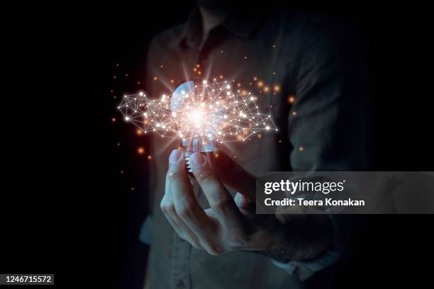 a male businessman standing with a light bulb looking for new creative ideas for a future business on a black background. idea concept with innovation and inspiration - bulb connections bildbanksfoton och bilder