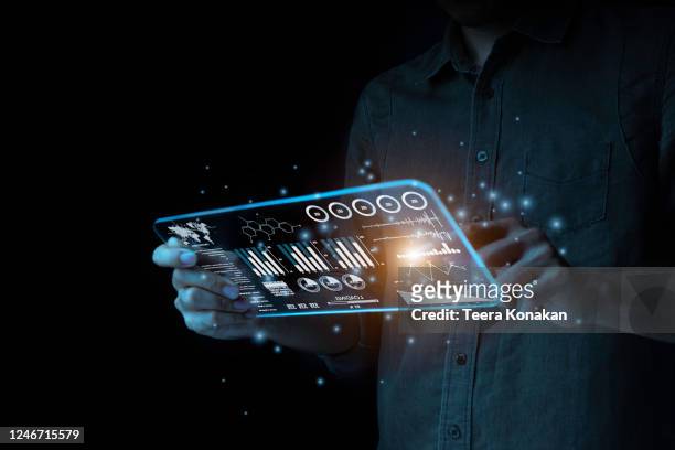 a businessman points to a hologram on his smartphone to analyze and find ways to plan his fast growing business on the black background. new generation technology concept - touch screen technology foto e immagini stock