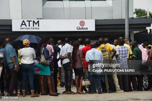 Dozens of people queue to withdraw new Naira notes from Automated Teller Machine at a bank premises in Lagos on February 1, 2023. - In October 2022...