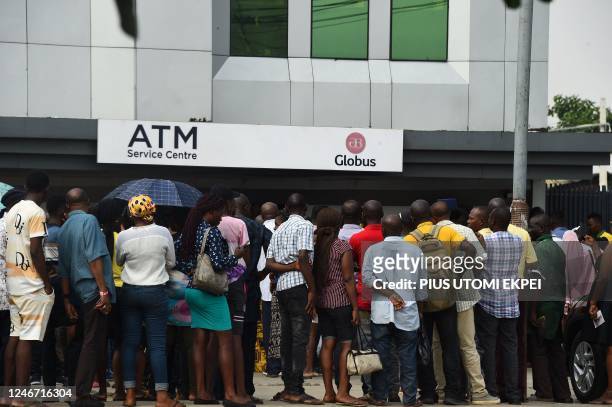 Dozens of people queue to withdraw new Naira notes from Automated Teller Machine at a bank premises in Lagos on February 1, 2023. - In October 2022...