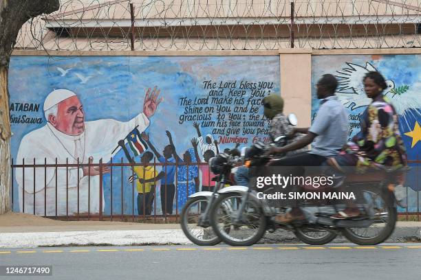 People on motorcycles ride past a mural depicting Pope Francis as preparations continue ahead of his visit in Juba, South Sudan, on February 01,...