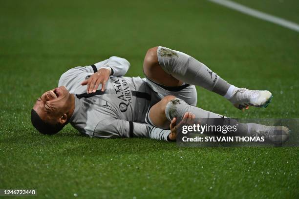 Paris Saint-Germain's French forward Kylian Mbappe lies on the ground after getting injured during the French L1 football match between Montpellier...