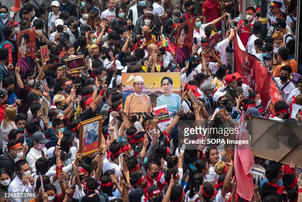 Protesters hold portraits of Aung San Suu Kyi and make three finger salutes during the demonstration. Burmese in Thailand gather outside the Myanmar...