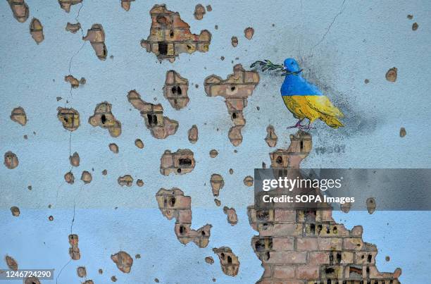 Graffiti by an Italian street artist TVboy can be seen on the shrapnel scrared wall of the House of Culture destroyed by the Russian army in town of...