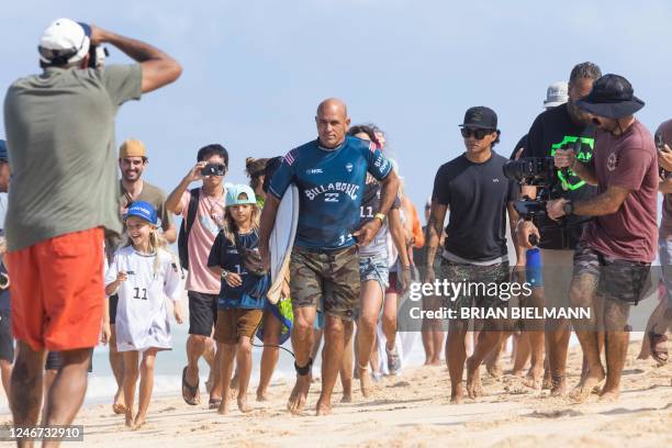 S surfer Kelly Slater is surrounded by fans as he walks to the water during the first day of the Billabong Pipeline Pro at Banzai Pipeline on the...