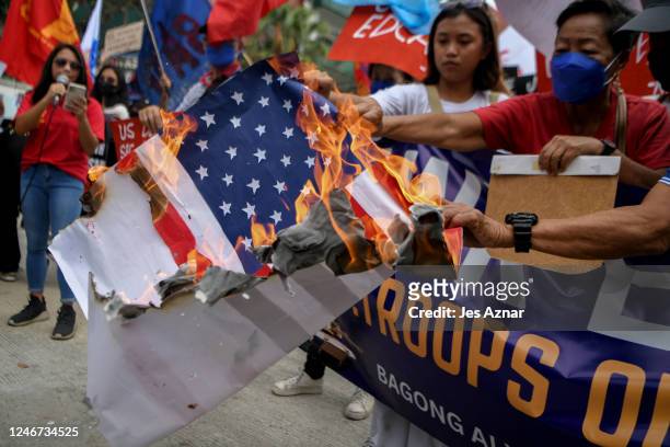 Activists burn an american flag as they stage a protest outside the gates of Camp Aguinaldo main military camp on February 2, 2023 in Manila,...
