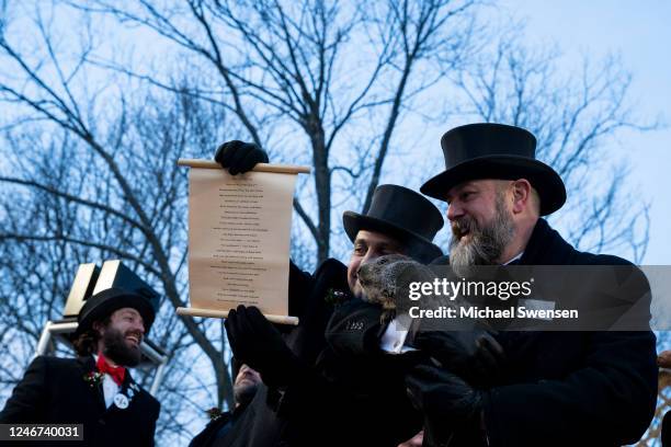 Vice President Dan McGinley shows a scroll to the crowd as Groundhog handler AJ Derume holds Punxsutawney Phil, who saw his shadow, predicting a late...