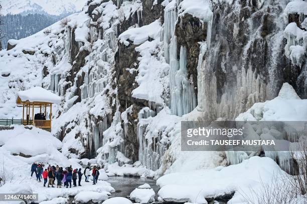 Tourists visit a frozen waterfall in the Drang area of Tangmarh on February 2, 2023.