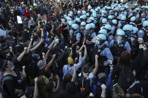 Police officers guarding the Trump International Hotel &amp; Tower hold back protesters on May 30 during a rally and march to remember the killing of...