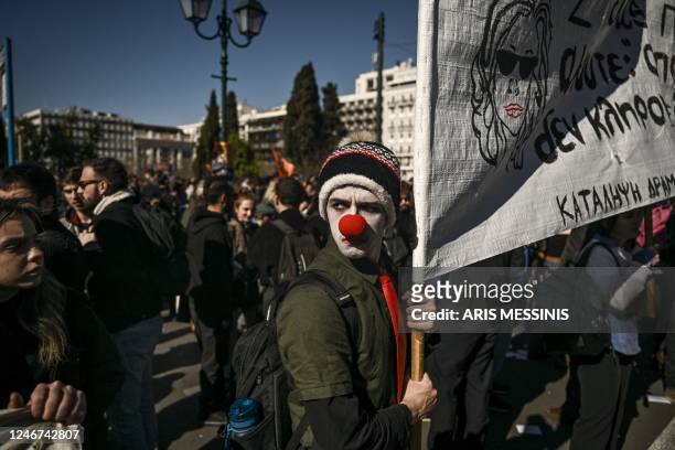 An artist wearing a clown nose holds a banner during a demonstration in front of the Greek parliament in Athens, on February 2, 2023. - Around one...