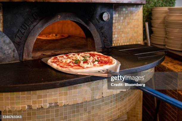 Chef uses a peel to place a Pizza Margherita into an oven at a pizzeria in Naples, Italy on Thursday, Feb. 2, 2023. Enjoying one of Italys classic...