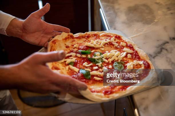 Chef places a Pizza Margherita onto a peel at a pizzeria in Naples, Italy on Thursday, Feb. 2, 2023. Enjoying one of Italys classic dishes has just...