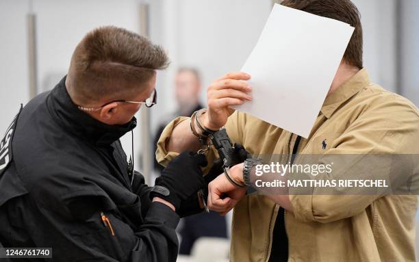 Judicial officer opens the handcuffs of defendant Rabieh R at the Higher Regional Court in Dresden, eastern Germany on February 3, 2023 prior to a...