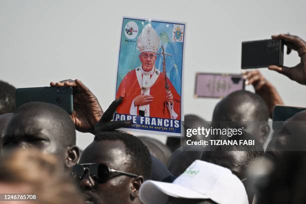 Man holds a picture of Pope Francis as a crowd gathers to welcome him upon his arrival at the Juba International Airport in Juba, South Sudan, on...