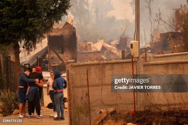 People cry next to a destroyed house during a fire in Santa Juana, Concepcion province, Chile on February 3, 2023. - Chile has declared a state of...