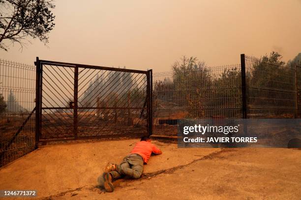 Man is seen on the ground during a fire in Santa Juana, Concepcion province, Chile on February 3, 2023. - Chile has declared a state of disaster in...