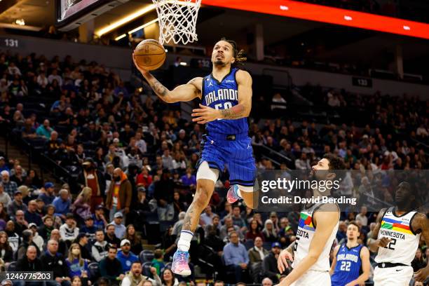 Cole Anthony of the Orlando Magic dunks the ball on an alley-oop while Austin Rivers of the Minnesota Timberwolves reacts in the first quarter of the...