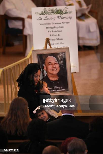 Kristenne Reidy, daughter of Valentino Alvero, holds daughter Joan Reidy, while Grace Reidy, lower smiles during the funeral of their father and...