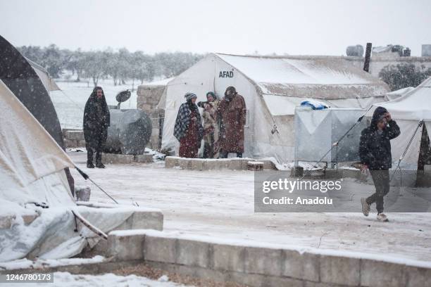 People stand outside tents during snowfall in a camp in Azez, Syria on February 04, 2023.